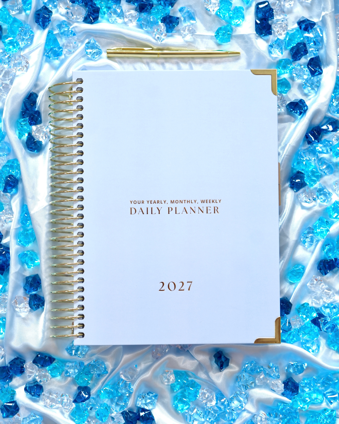 Blue 2027 Daily Spiral Planner with gold spiral binding among blue crystals
