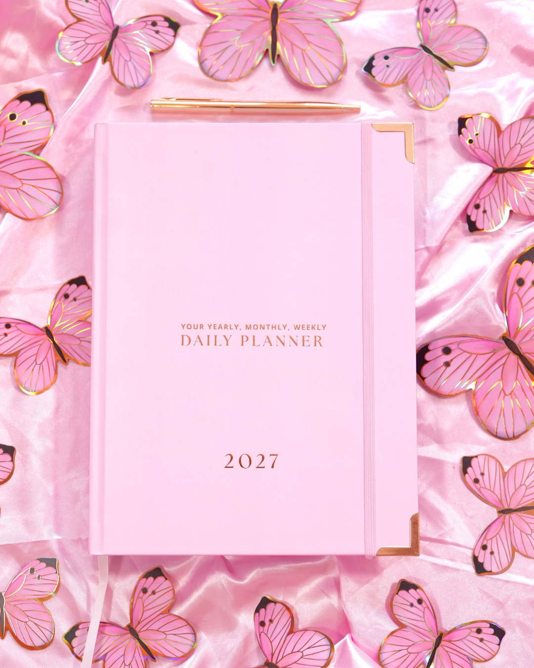 Pink 2027 Non-Spiral Daily Planner with gold corners surrounded by pink butterflies