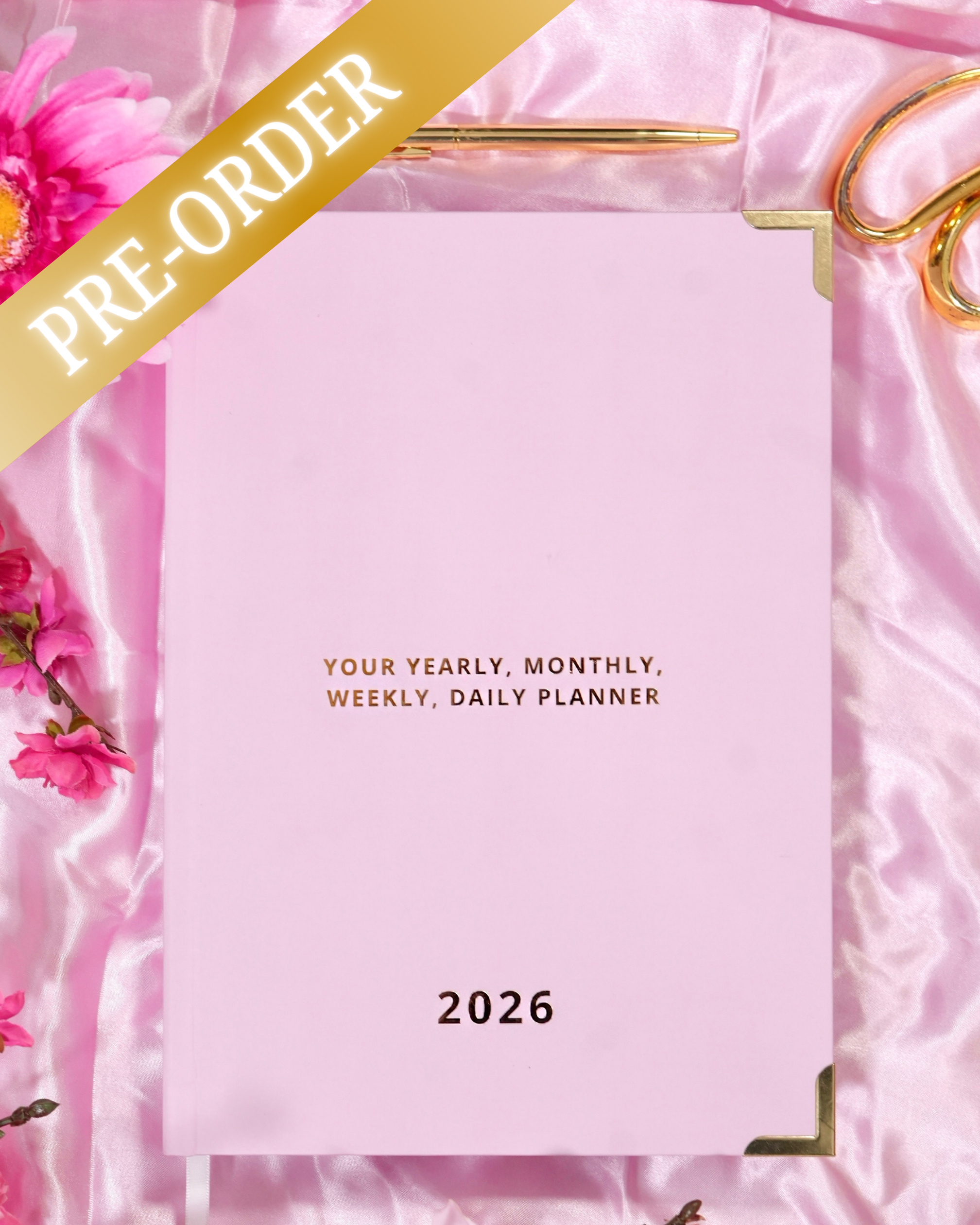 Pink planner with 'PRE-ORDER' text on a pink satin background with flowers and scissors.