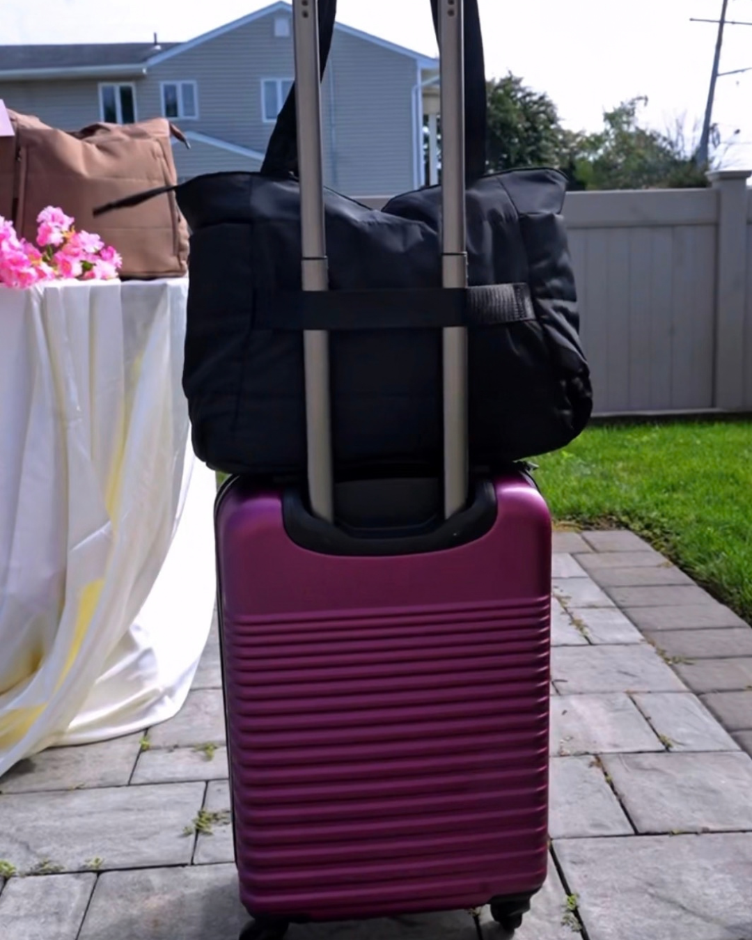 Black Travel Tote slipped over the handle of a purple suitcase
